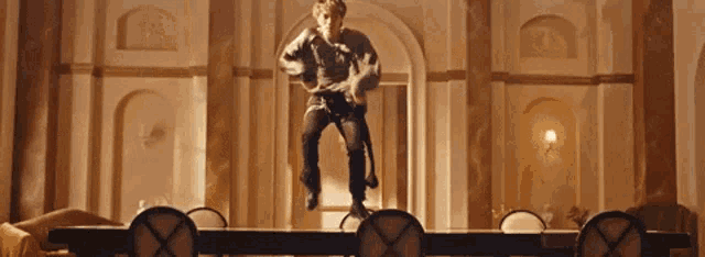 a man is jumping over a table in a room .