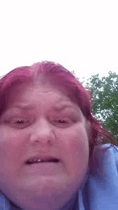 a woman with red hair is making a funny face while wearing a blue shirt .