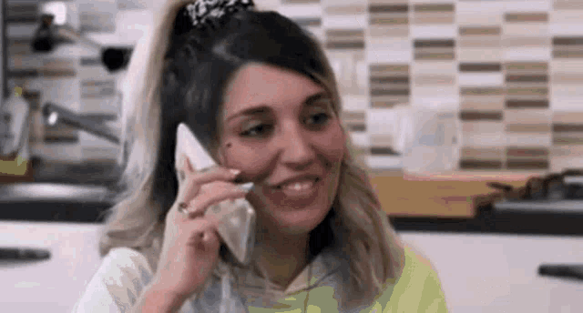 a woman is smiling while talking on a cell phone .