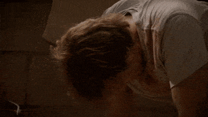 a man in a white shirt is doing push ups on the floor in a dark room .