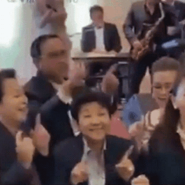 a group of people in suits are clapping and smiling