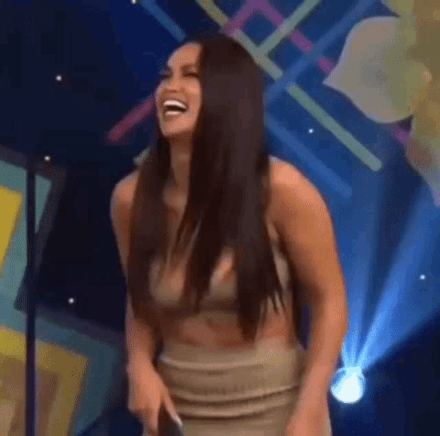 a woman is laughing on a stage in a dress .