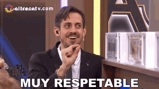 a man in a suit says muy respetable in front of a sign that says match game