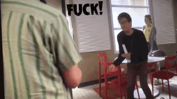 a man in a striped shirt is standing in a room with a sign that says fuck