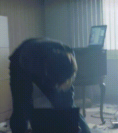 a person is kneeling down in a dark room with a laptop on a table .