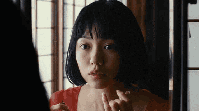 a woman looking at herself in a mirror with a red shirt on