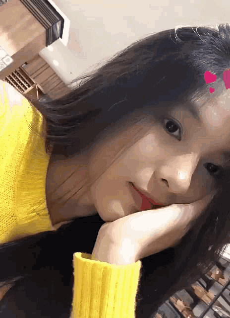 a girl in a yellow sweater has her hand on her chin
