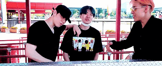 three men are standing next to each other at a roller coaster .