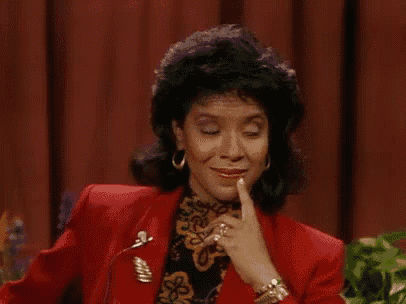 a woman in a red jacket is making a funny face while holding her finger to her mouth .