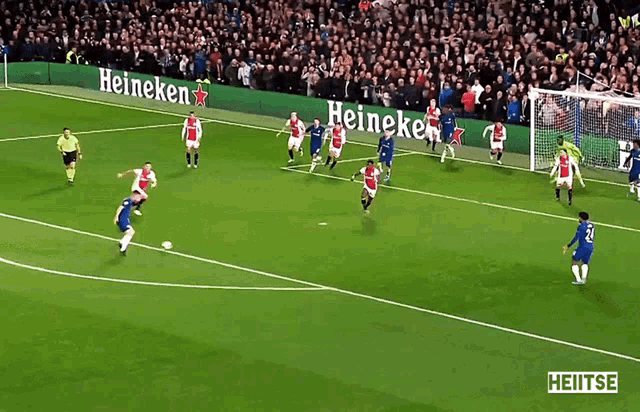 a soccer game is being played on a field with heineken ads on the sidelines