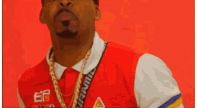 a man wearing a red and white shirt with a gold chain around his neck