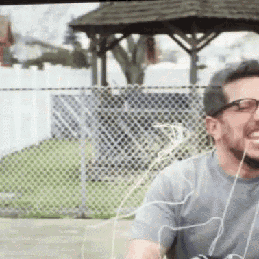 a man wearing glasses and headphones is smiling in front of a gazebo