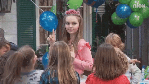 a girl with a flower crown on her head stands in front of a group of children at a nick party