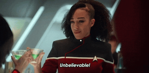 a woman in a star trek uniform is holding a martini and saying unbelievable .