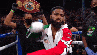 a man in a boxing ring holds up a belt that says world champion