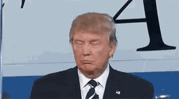 donald trump is making a funny face while sitting in front of a plane .