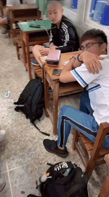 a group of people are sitting at desks in a classroom with a laptop .