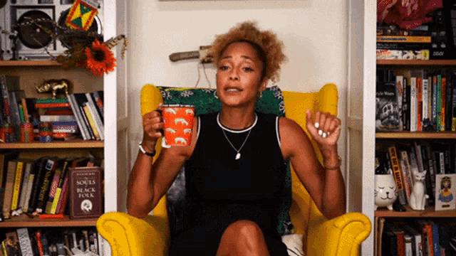 a woman is sitting in a yellow chair holding a mug that says " souls " on it