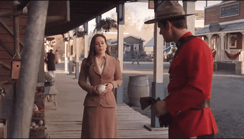a man in a red uniform is standing next to a woman in a brown suit