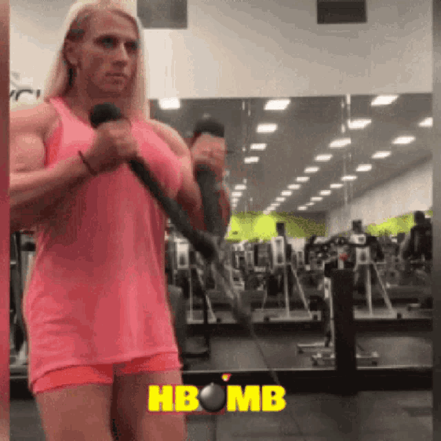 a woman in a pink tank top is doing exercises in a gym with the words hbomb on the bottom right