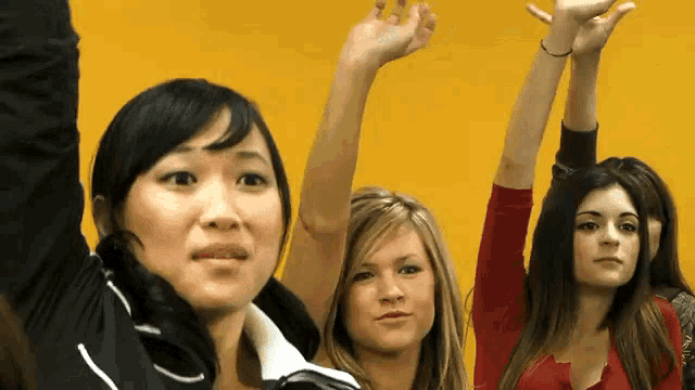 three women are raising their hands in the air