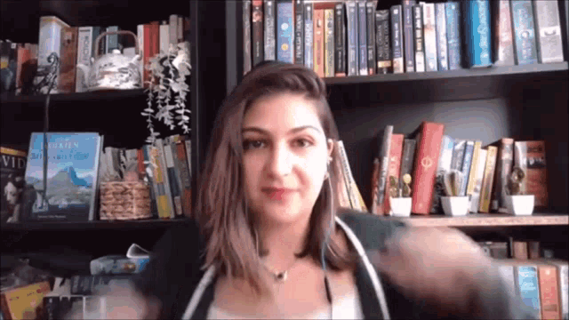a woman is standing in front of a bookshelf with a book titled the golden compass on it