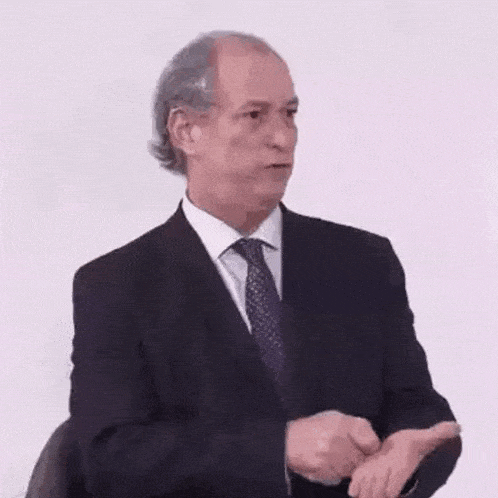 a man in a suit and tie is making a funny face while talking .