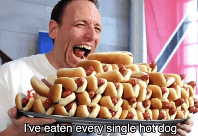 a man is holding a tray of hot dogs with the words i 've eaten every single hot dog below him