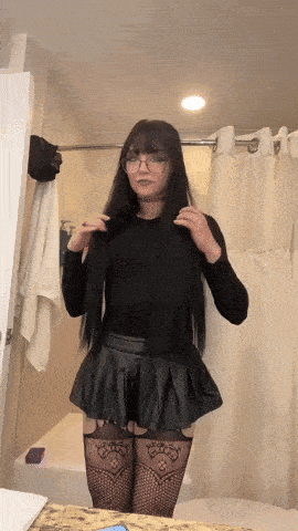 a woman in a black skirt and fishnet stockings is standing in front of a shower curtain