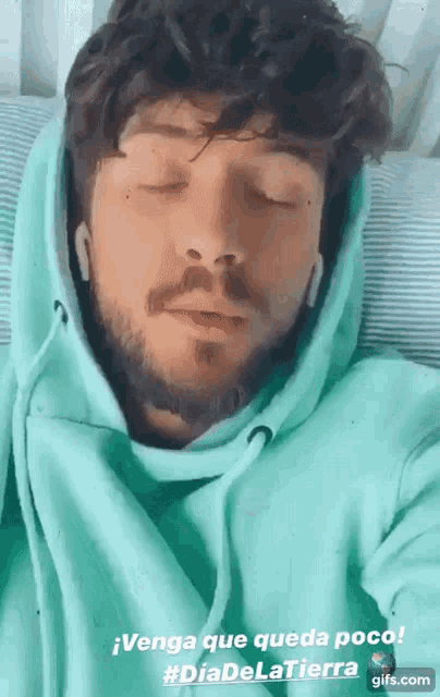 a man with a beard wearing a green hoodie is sleeping