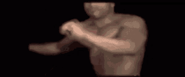 a blurry picture of a man without a shirt standing in the dark .