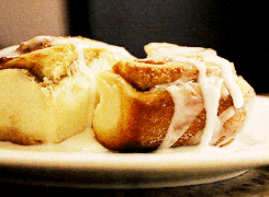 two cinnamon rolls on a white plate with icing on them