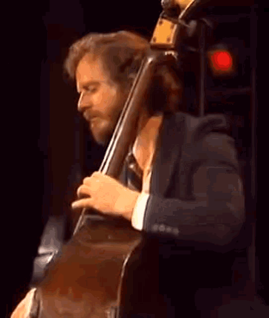 a man is playing a double bass on a stage .