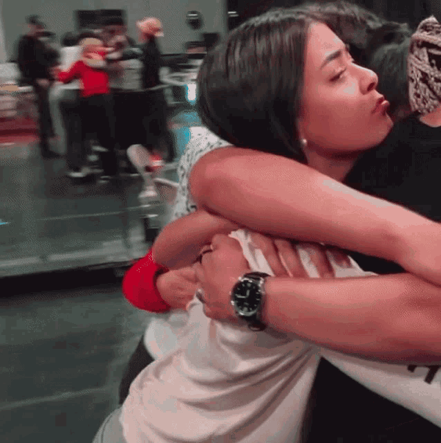 a woman wearing a watch is hugging a man