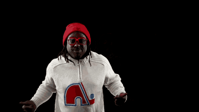 a man wearing a red hat and glasses is wearing a white sweater with the letter n on it