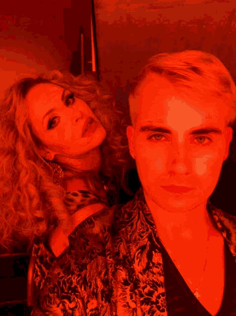 a man and a woman are standing next to each other in red light