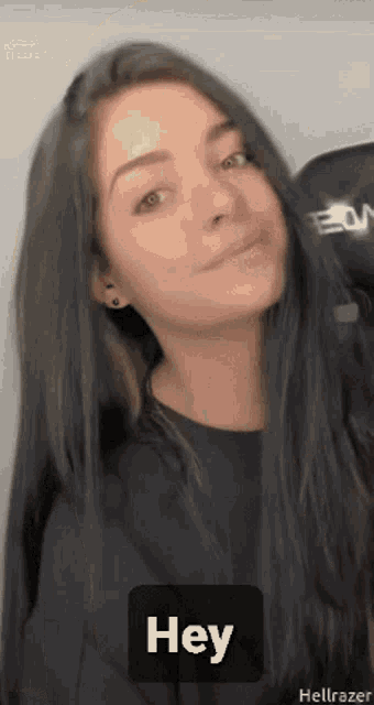 a woman with long black hair is smiling and says hey