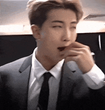 a man in a suit and tie is eating a piece of food .