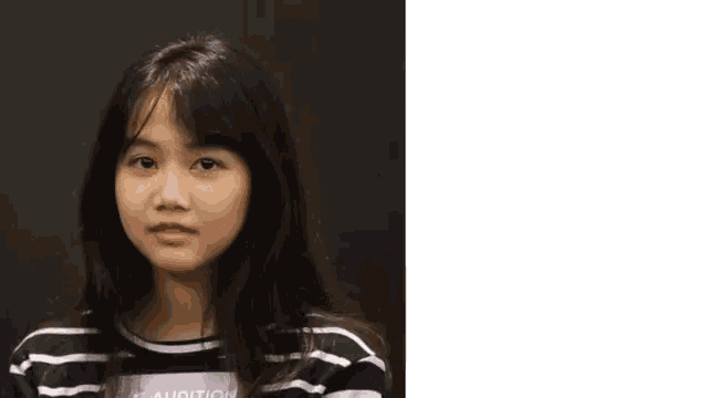 a young girl with long black hair is wearing a striped shirt and smiling .