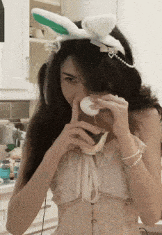 a woman wearing bunny ears and a corset is eating a watermelon