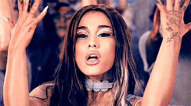 ariana grande is wearing a choker and holding her arms up in the air .