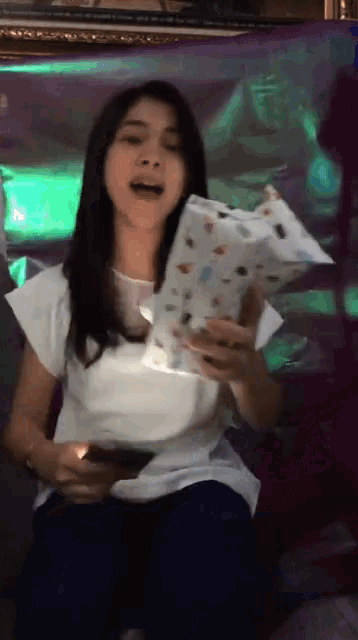 a woman in a white shirt is singing into a microphone