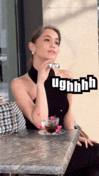 a woman sits at a table with a cup of coffee and a sticker that says " ughhhh "