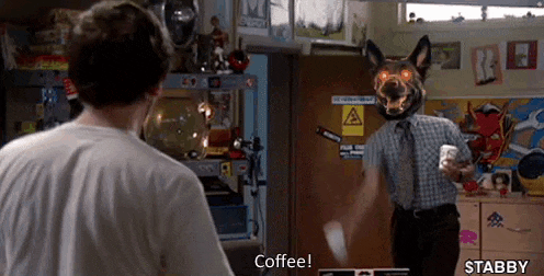 a man wearing a dog mask is holding a cup of coffee while talking to another man .