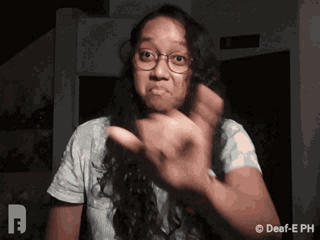 a woman wearing glasses and a white shirt is making a funny face