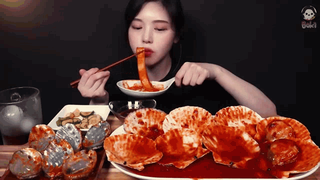 a woman is eating a plate of food with chopsticks and a skull in the background