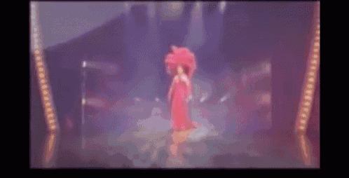 a woman in a red dress and hat is standing on a stage .