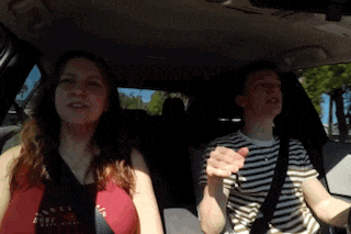 a man and a woman are sitting in a car and the woman is wearing a red shirt that says abercrombie