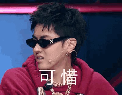 a man wearing sunglasses and a red hoodie with chinese writing on it .