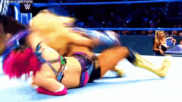 two women are wrestling in a wrestling ring and one of them is wearing a pink outfit